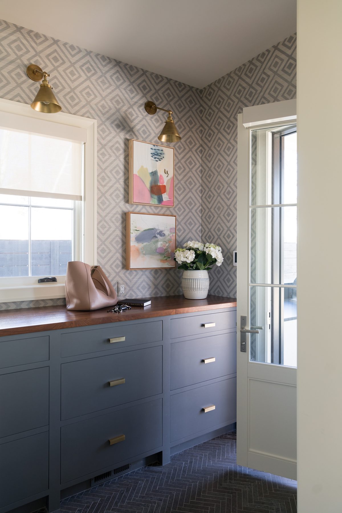 Navy custom cabinetry in a laundry and mudroom with patterned tile floor